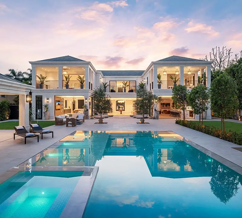 Contemporary luxury estate with a floodlit pool at dusk, representing the calibre of homes marketed through Luxury Portfolio International